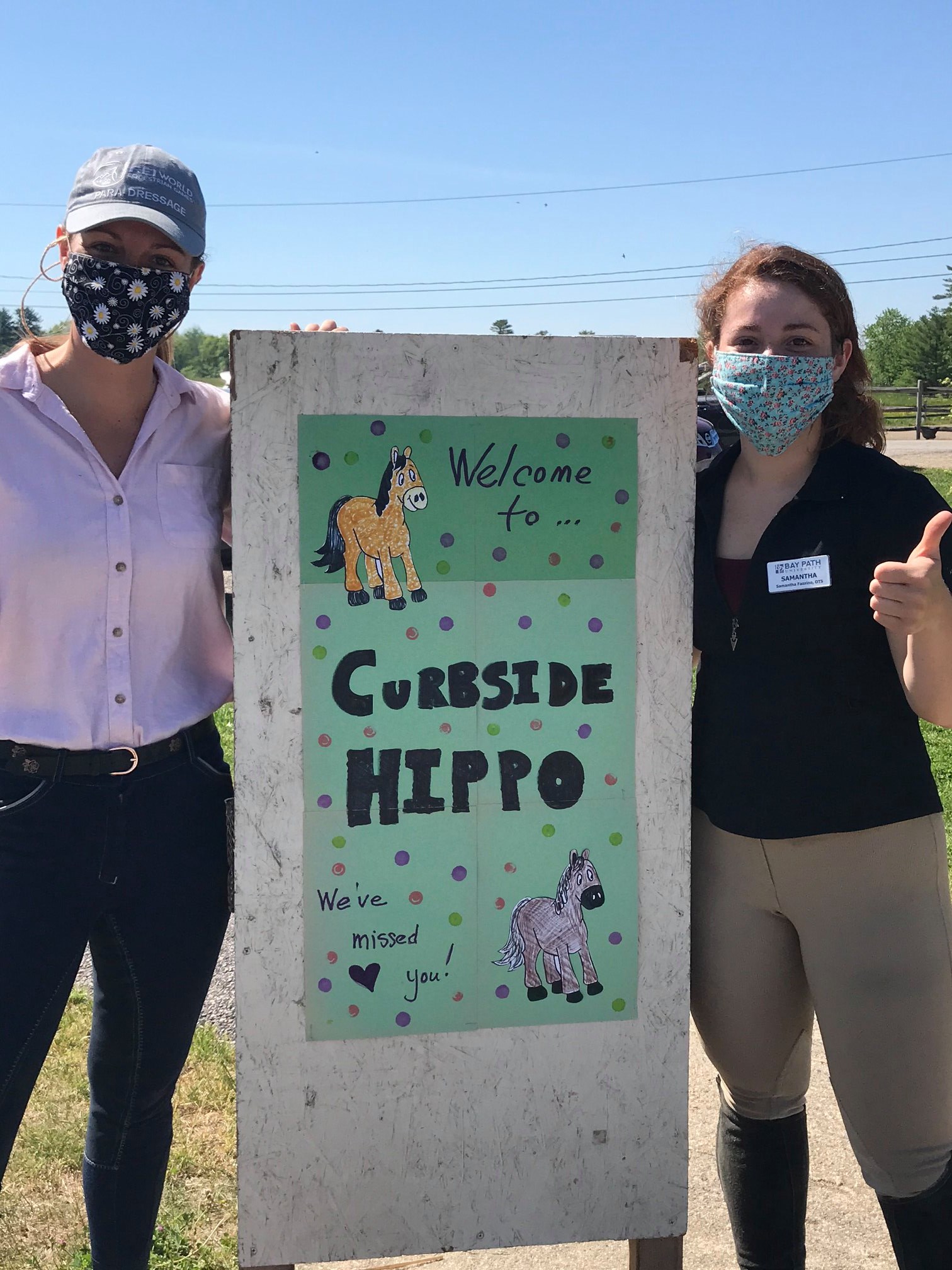 Photo of 2 interns holding a "curbside hippo" sign.
