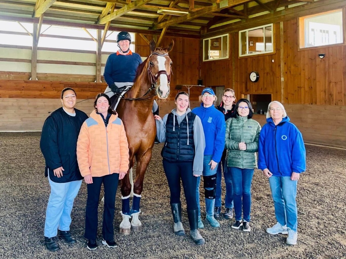 Group of OT students around a disabled woman on a horse